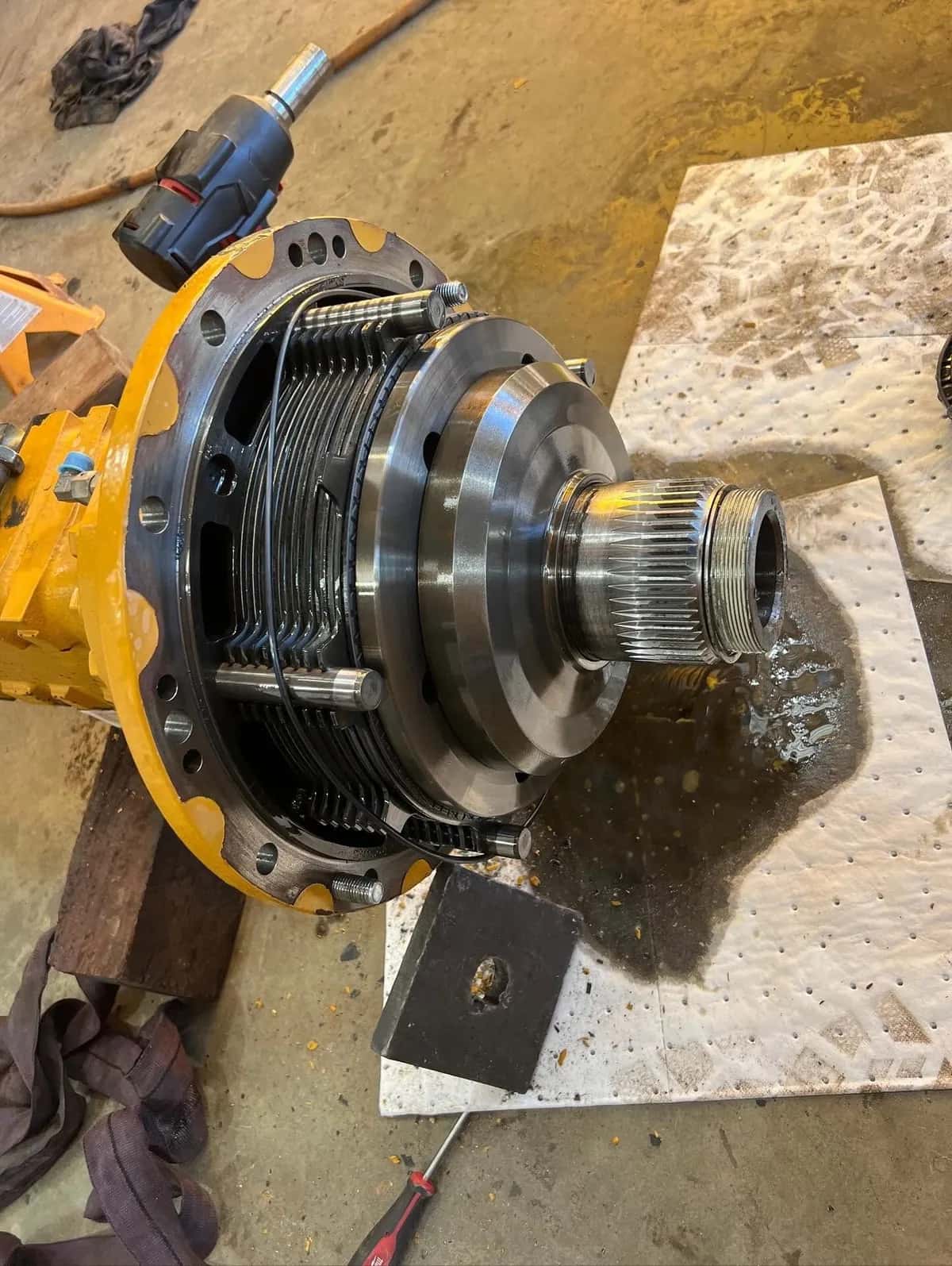 The clutch plate stack and splined shaft of a differential on an absorbent workshop mat.