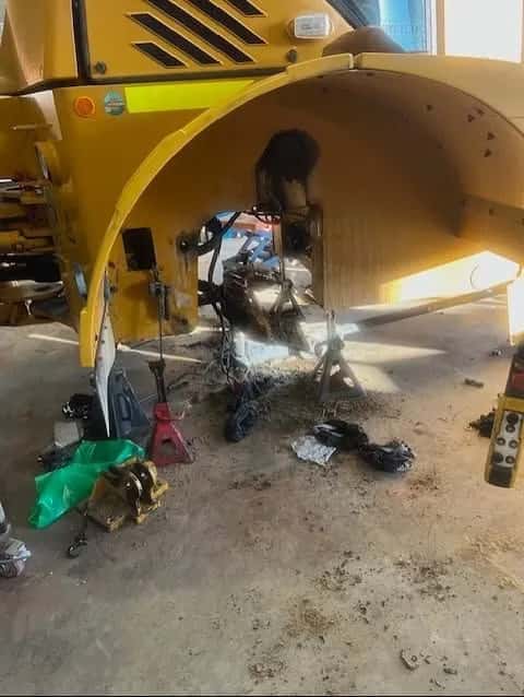 The rear of a yellow Hydrema 922 dump truck with the differential removed and stands holding the chassis.