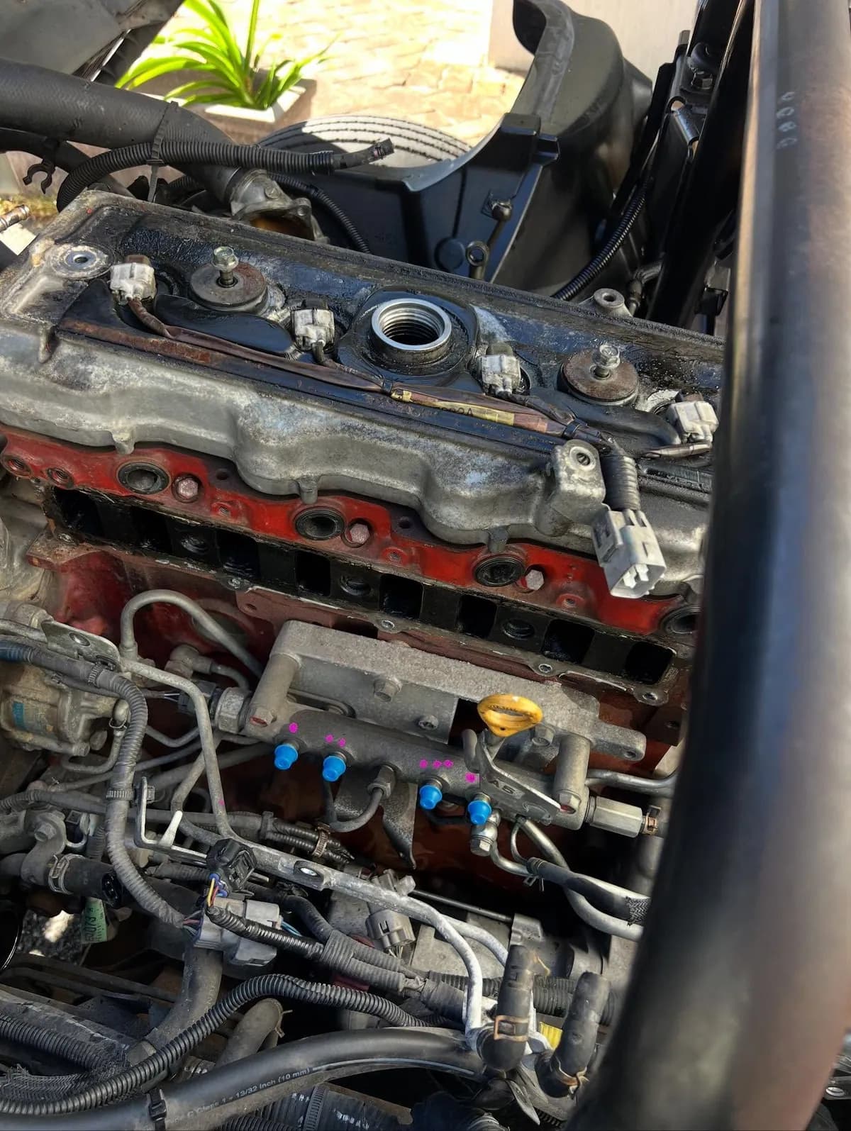 The top of a red Hino diesel engine with injector lines and blue injector caps, as found before the head work.