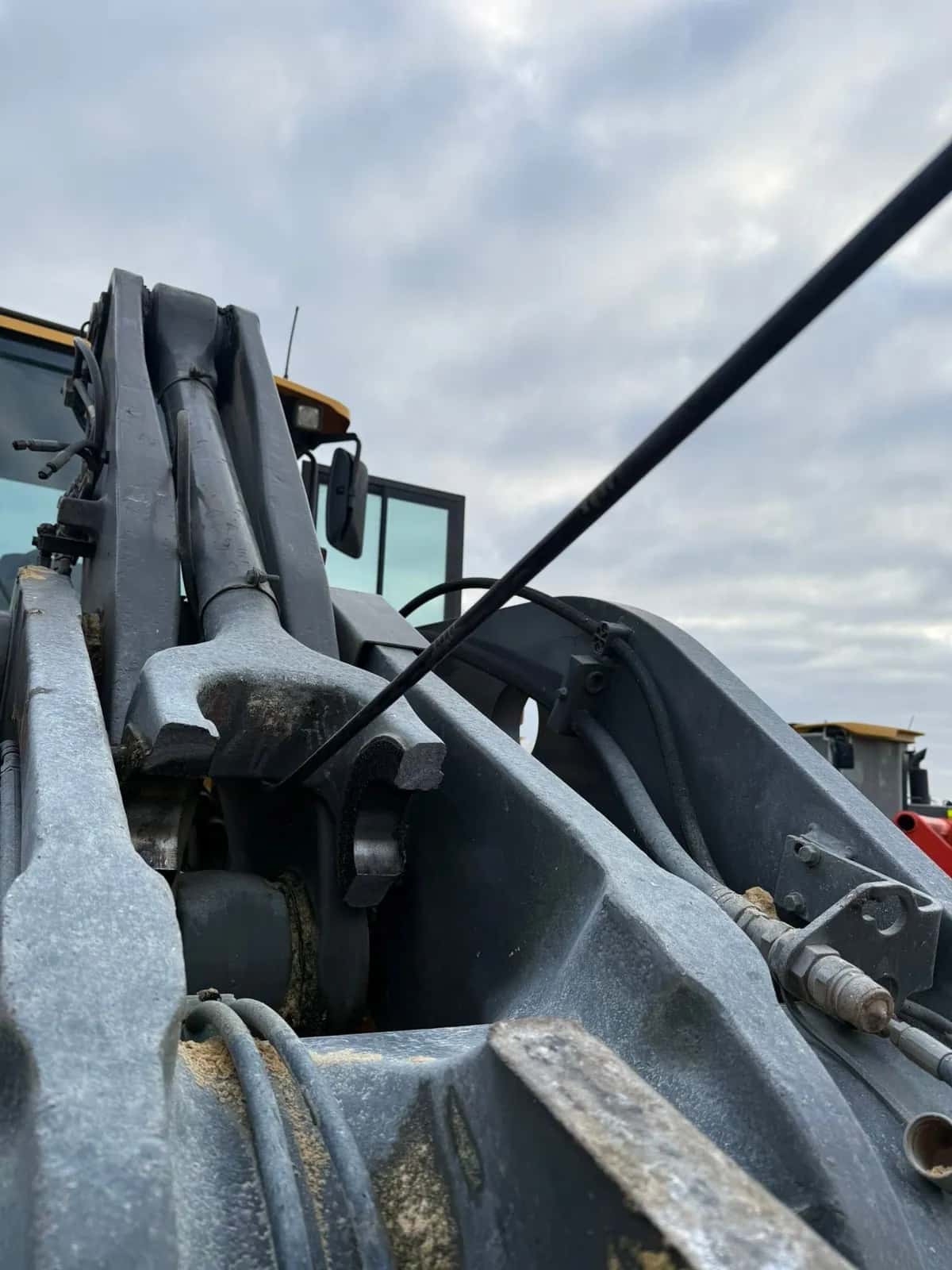 Wheel loader lift arm pivots under a cloudy sky before the work.